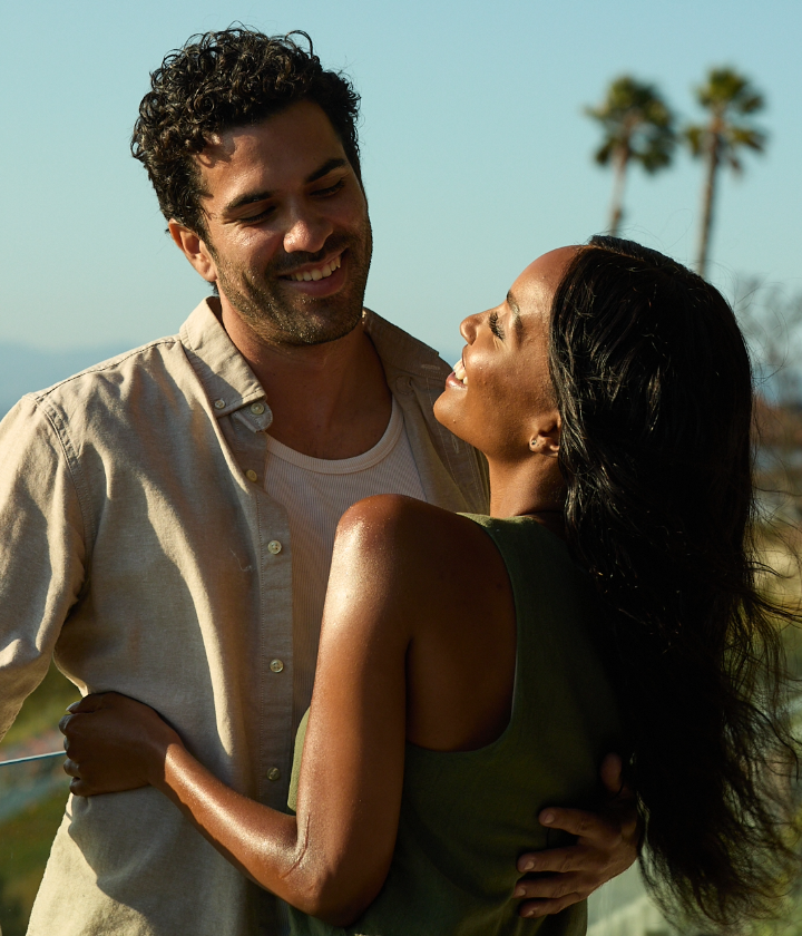 Man and woman embracing with palm trees in the background. Mello magnesium for deeper sleep and balance.