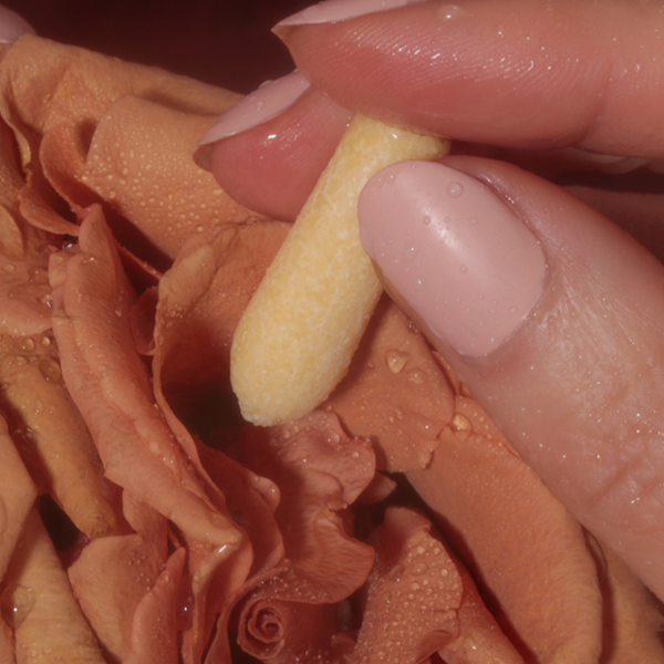 Foria Intimacy Melts with CBD Close-up of a hand holding a melt over a textured flower. 