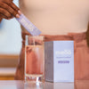 Person pouring a mello magnesium into a glass of water with the mello box in the background.