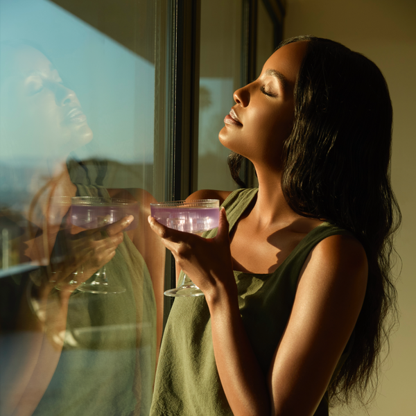 Foria Mellö Magnesium pouch set Woman holding magnesium glass, looking out window. 