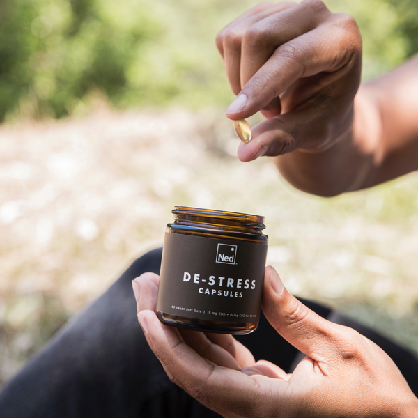 Foria De-Stress Capsules outdoors with person holding supplement