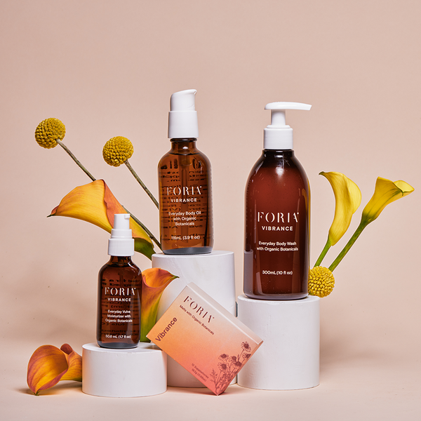 Foria Midlife Magic Set products with flowers on a beige background made for hydration and supporting menopause symptoms