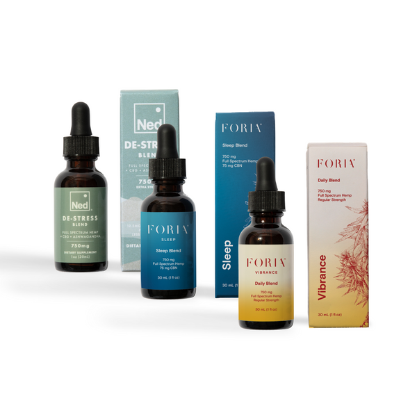 Three bottles of Foria products with their packaging on a white background